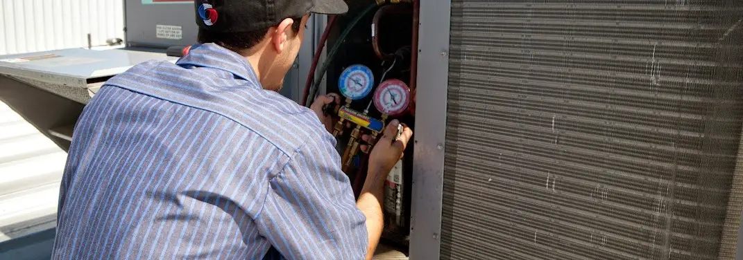 HVAC technician servicing a condenser unit in Fishkill